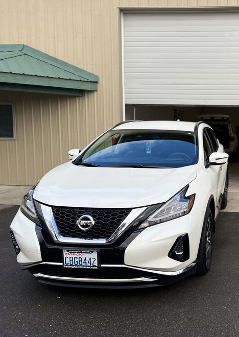 A white Nissan Murano is parked in front of a garage door.