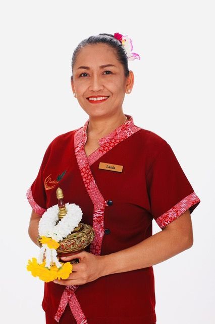 Eine Frau in einem roten Hemd hält eine Blumengirlande