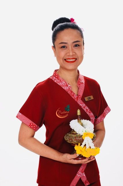 Eine Frau in einem roten Hemd lächelt und hält Blumen