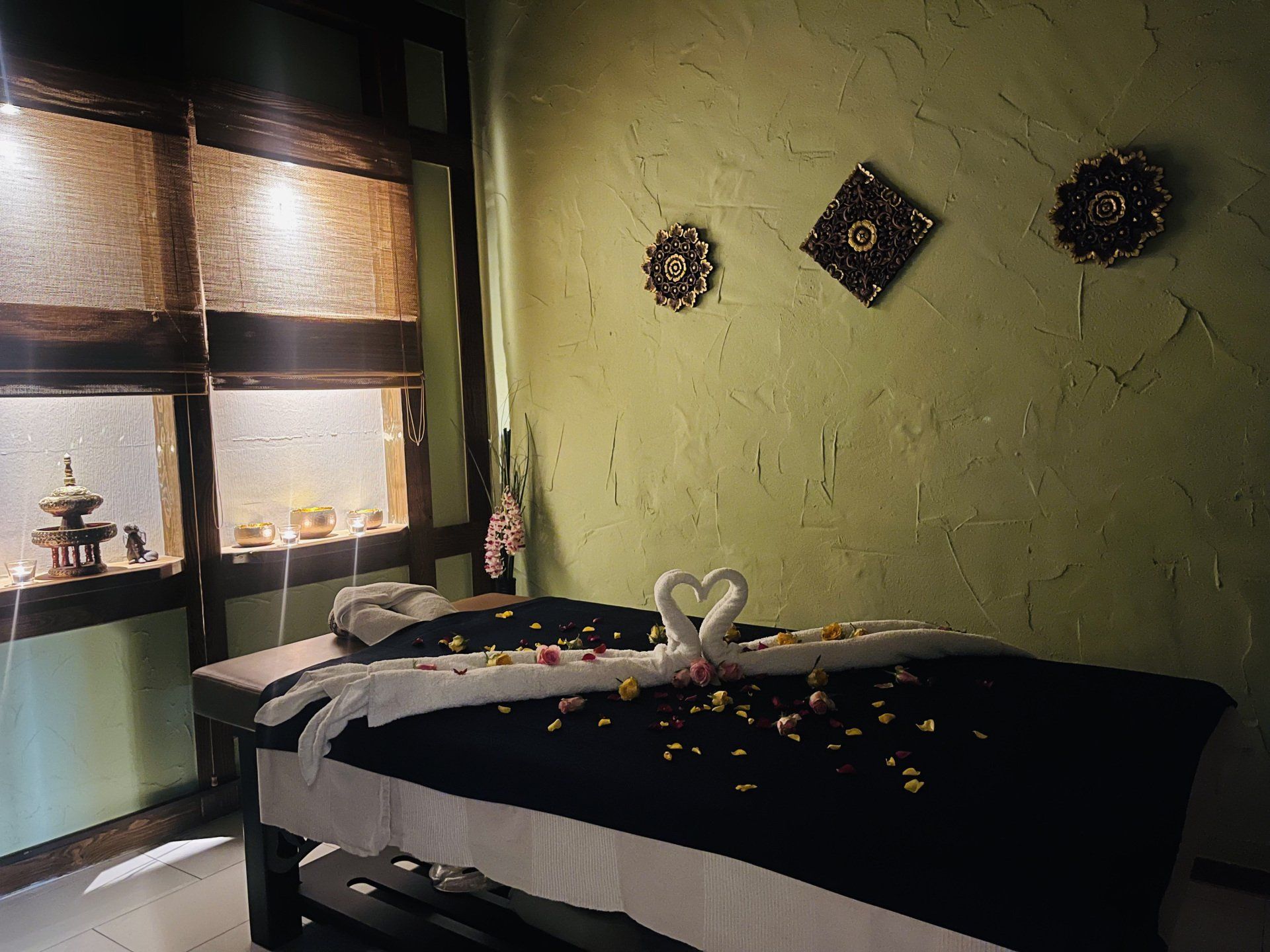 Eine Massageliege in einem mit Handtüchern und Blumen dekorierten Raum.