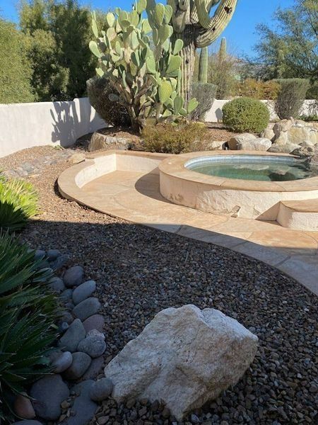 A desert landscape with a spa, a large cactus, and a rock garden.