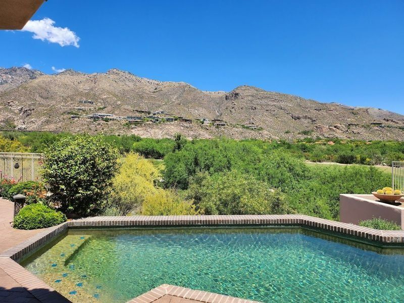 Pool with clear water, looking out at a mountain range and green landscape on a sunny day.