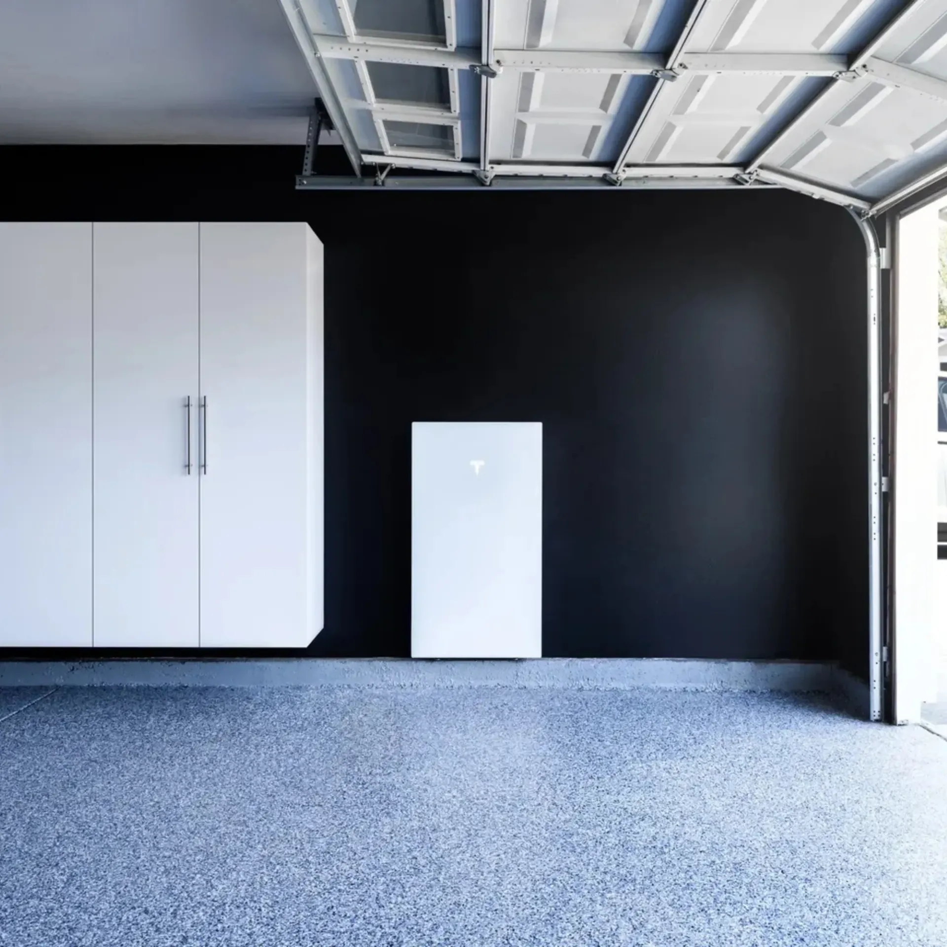 OE Services LLC - An empty garage with black walls and white cabinets