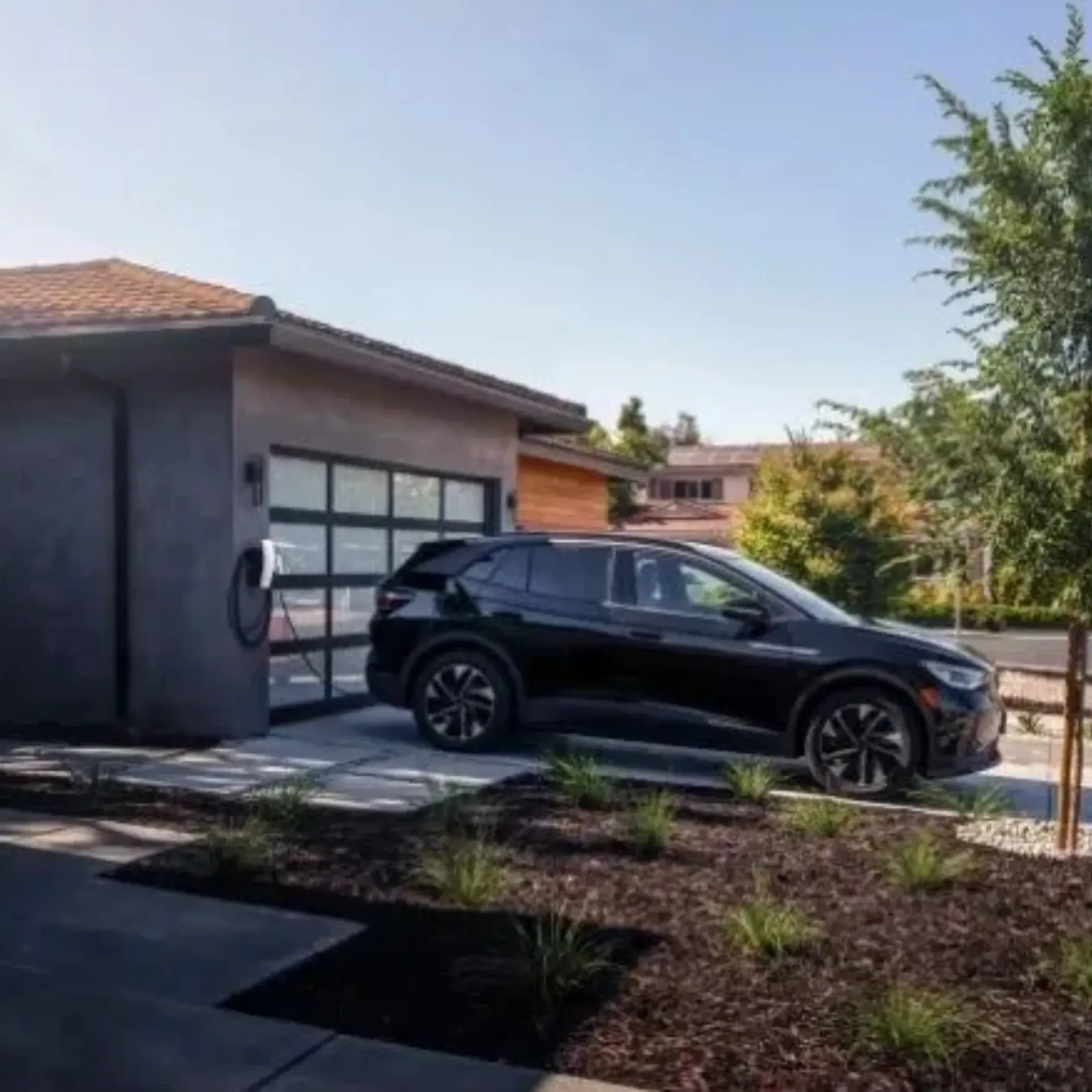 OE Services LLC - A black car is parked in front of a garage door.