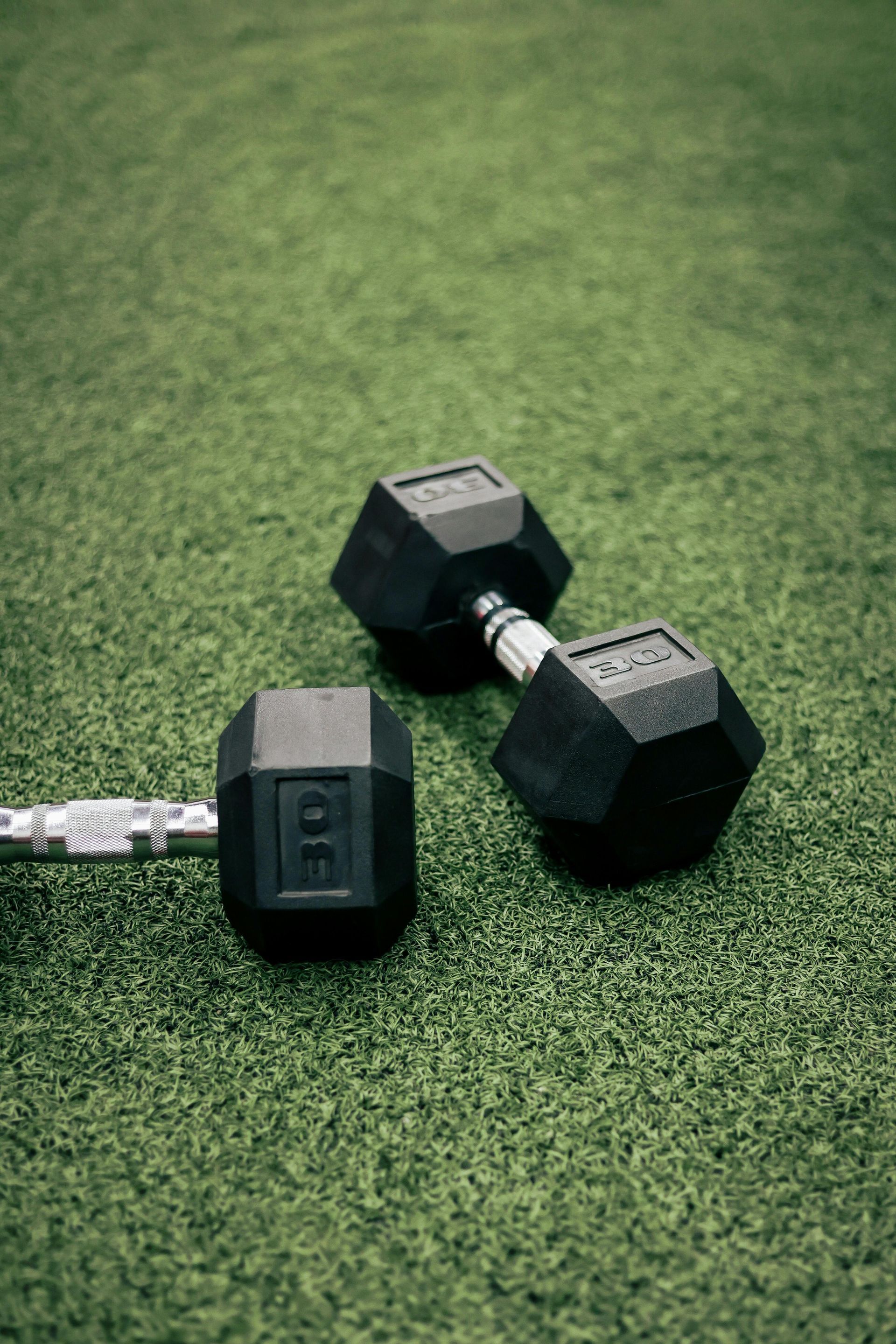 Black 5 kg dumbbell on green turf.