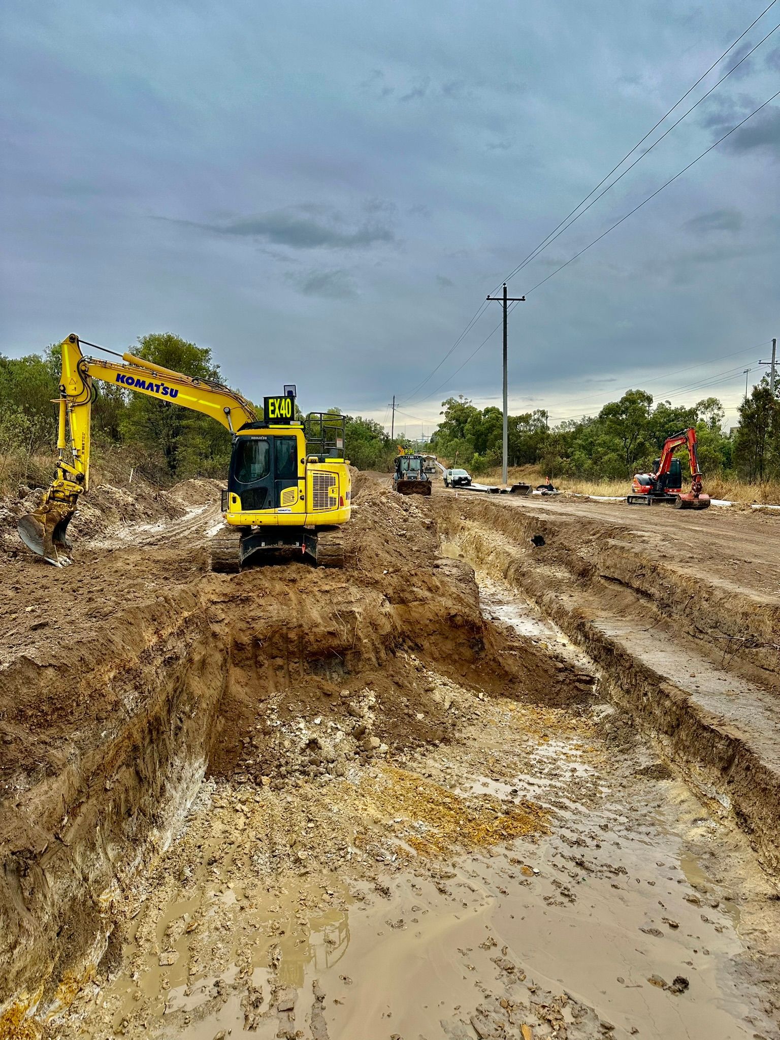 A Yellow Excavator is Digging a Hole in the Dirt — Precise Plumbing & Excavations Pty Ltd in Bowen, QLD