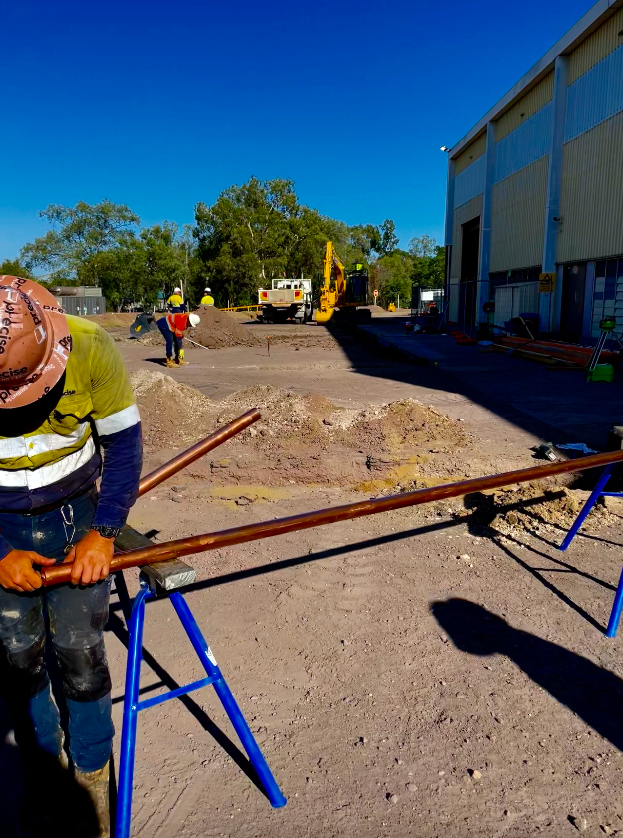 A Person is Holding a Wrench Surrounded by Pipes and Valves — Precise Plumbing & Excavations Pty Ltd in Bowen, QLD