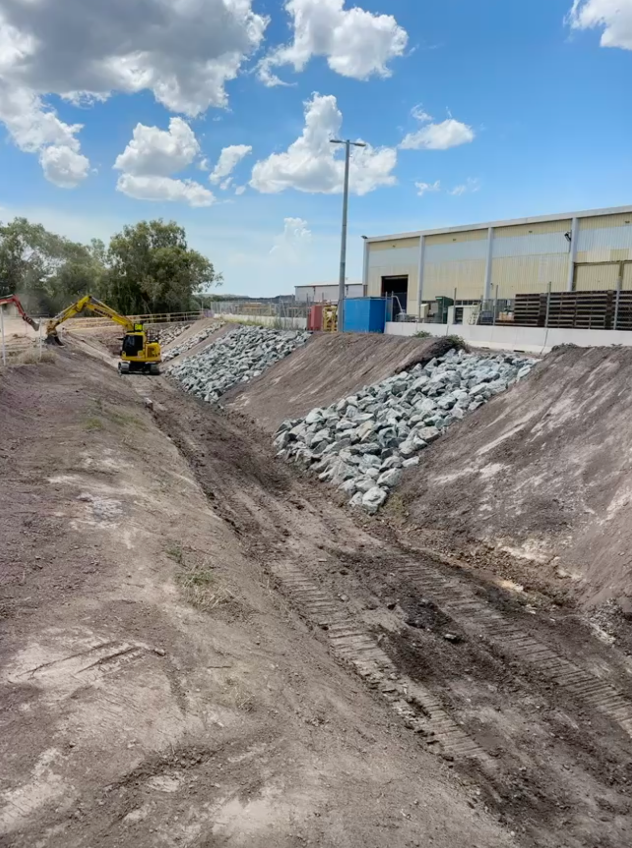 A Construction Site With Concrete Pipes and a Bulldozer in the Background — Precise Plumbing & Excavations Pty Ltd in Bowen, QLD