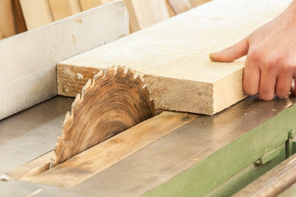 A Person is Cutting a Piece of Wood With a Circular Saw — Precise Plumbing & Excavations Pty Ltd in Bowen, QLD