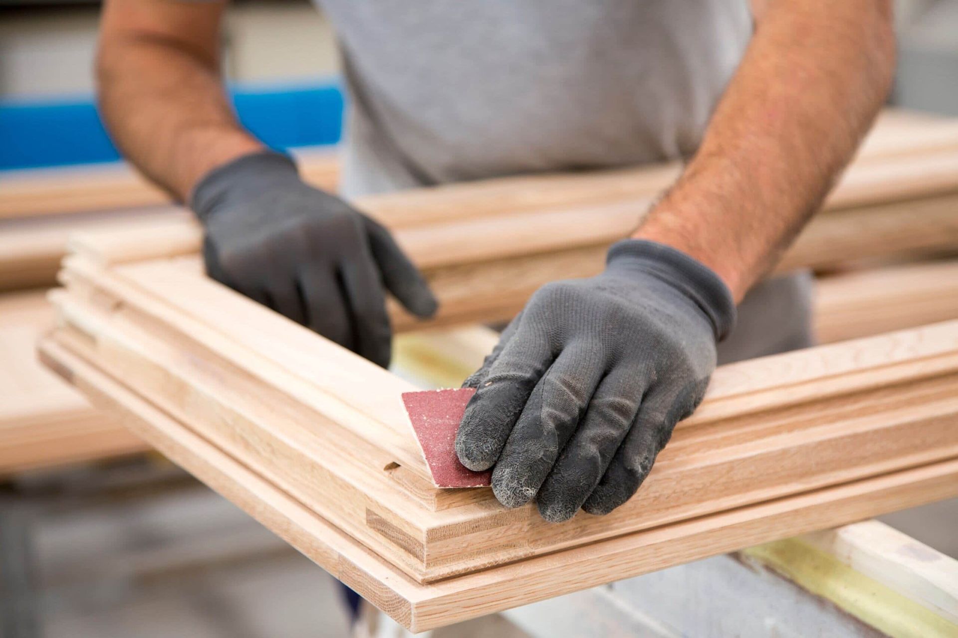 A Man Wearing Gloves is Sanding a Piece of Wood — Precise Plumbing & Excavations Pty Ltd in Bowen, QLD