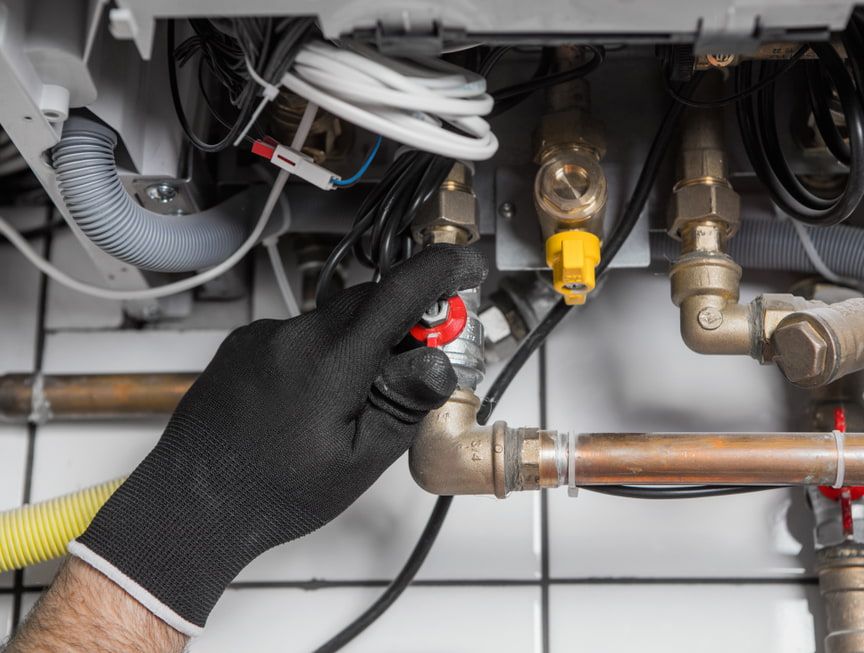 A Plumber is Working on a Boiler With a Screwdriver — Precise Plumbing & Excavations Pty Ltd in Bowen, QLD