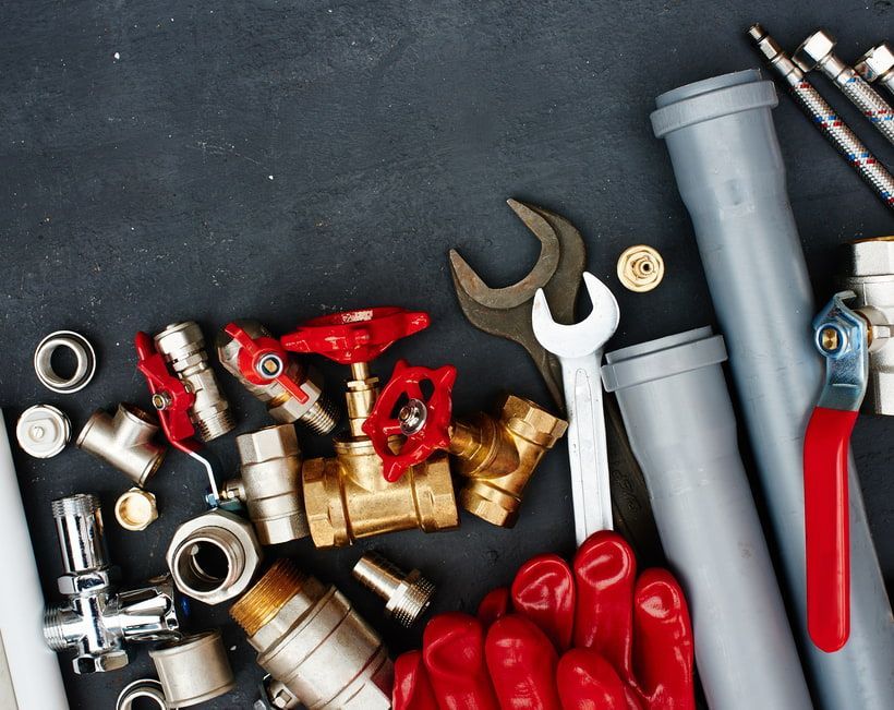 A Person is Holding a Wrench Surrounded by Pipes and Valves — Precise Plumbing & Excavations Pty Ltd in Bowen, QLD