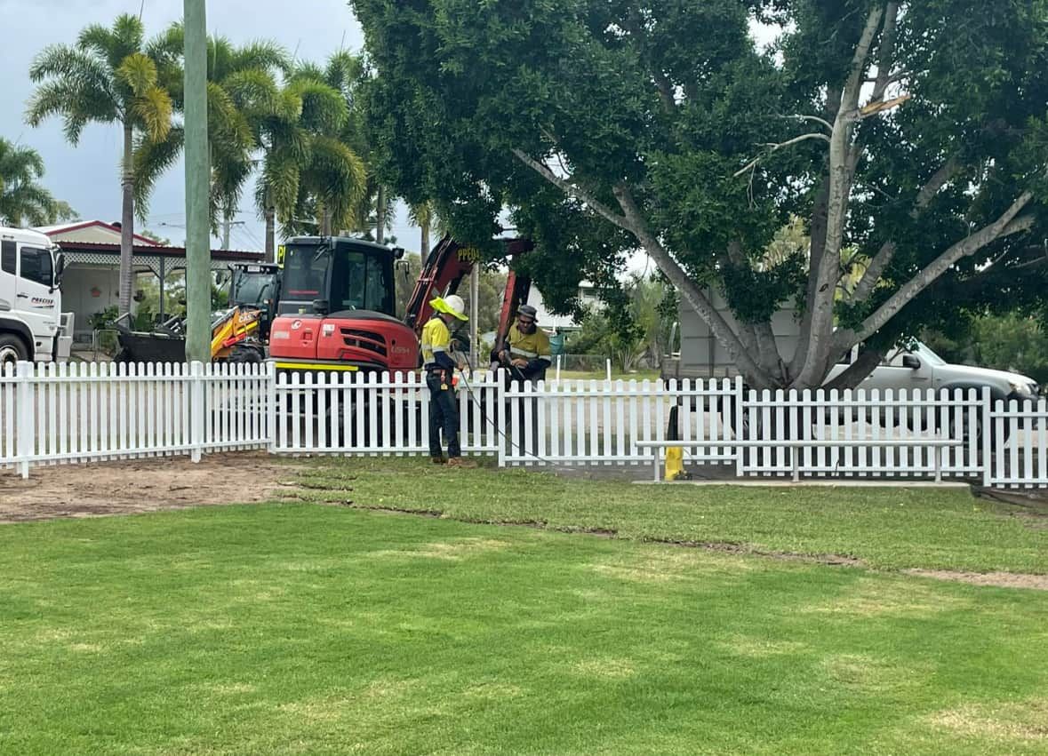 A Man is Standing in Front of a White Picket Fence — Precise Plumbing & Excavations Pty Ltd in Bowen, QLD