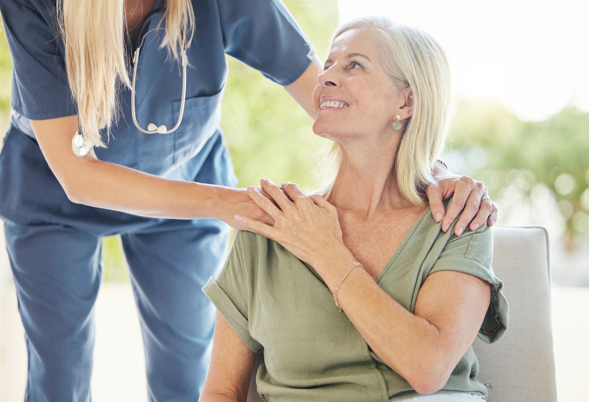 A nurse is putting her arm around an older woman 's shoulder.