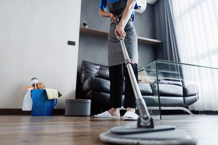 A woman is cleaning the floor with a mop in a living room.