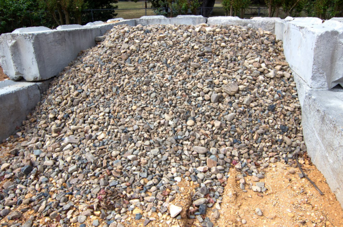 Pile of mixed gravel and rocks in a stone-lined bed outdoors