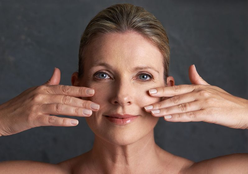 a woman is touching her face with her hands and smiling .