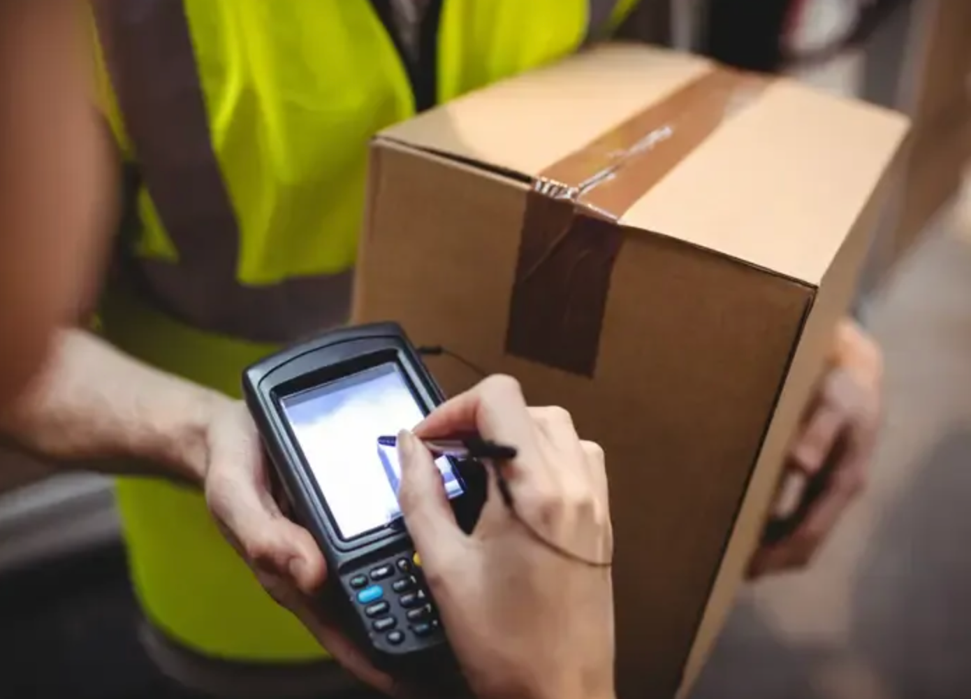 Delivery worker scanning a cardboard box barcode with a handheld device