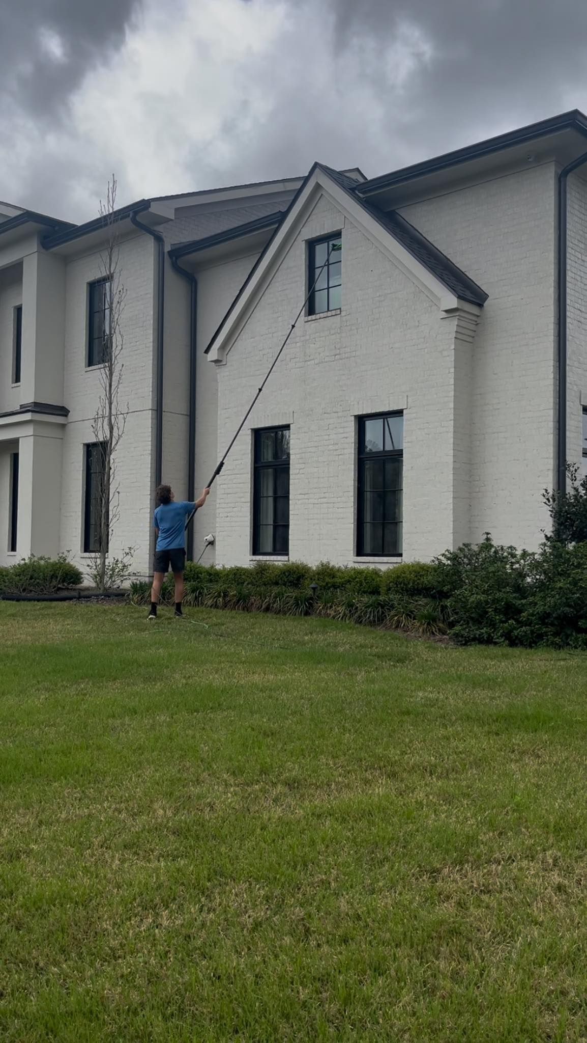 A man is cleaning the windows of a large white house.