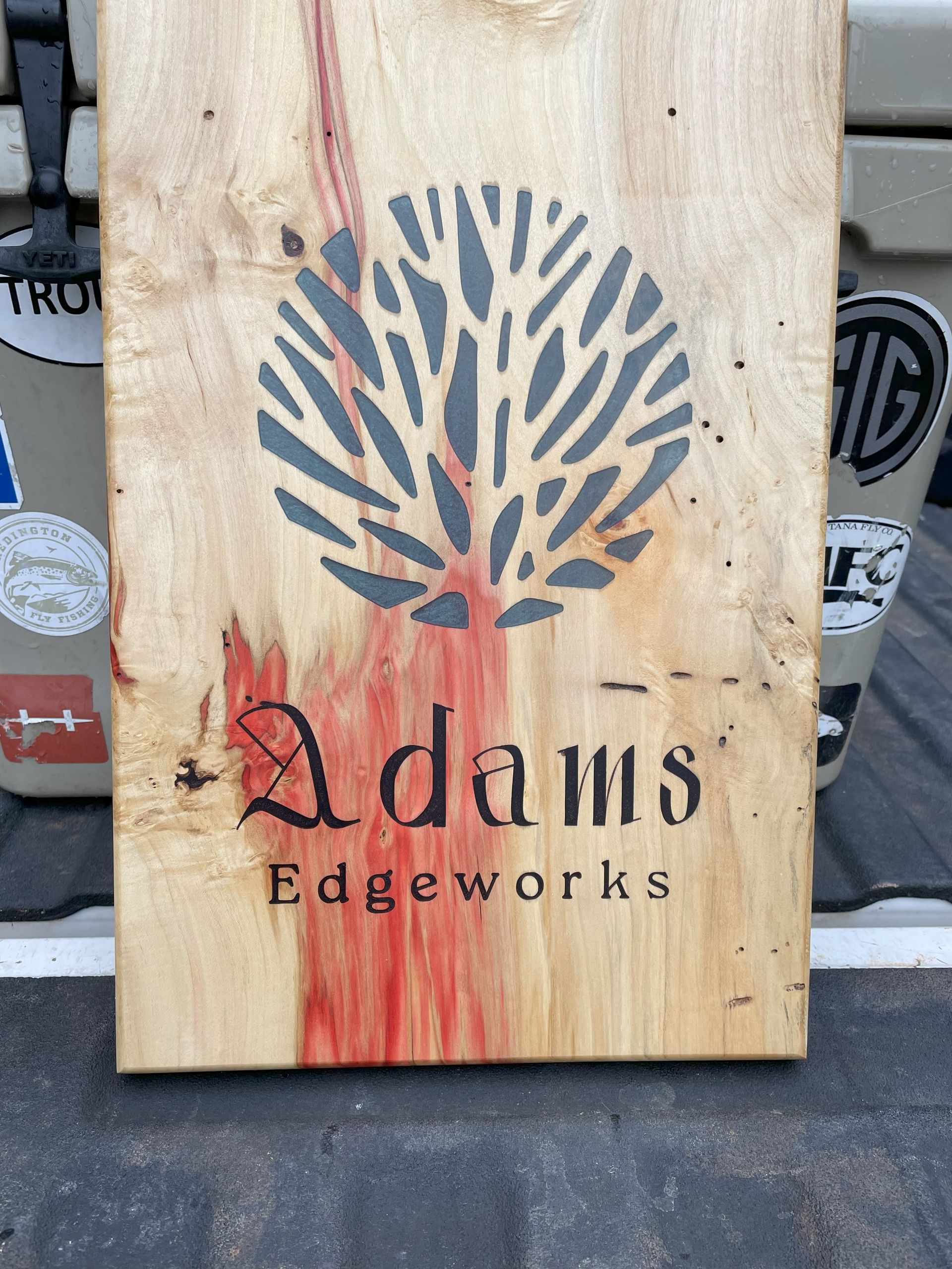A wooden sign that says adams edgeworks on it