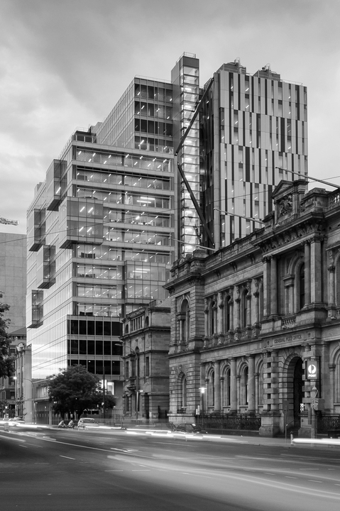 Modern and historic buildings along an Adelaide city street, viewed at dusk.