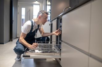 professional plumber installing new dishwasher