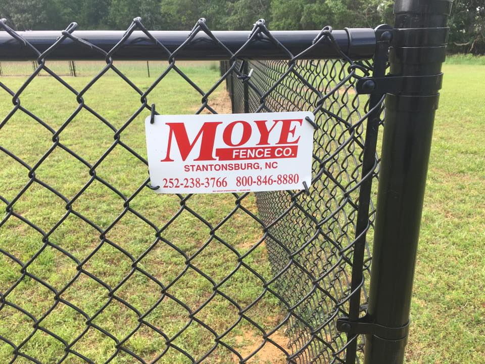 Black chain-link fence with a sign for Moye Fence Co. in front of a grassy area.