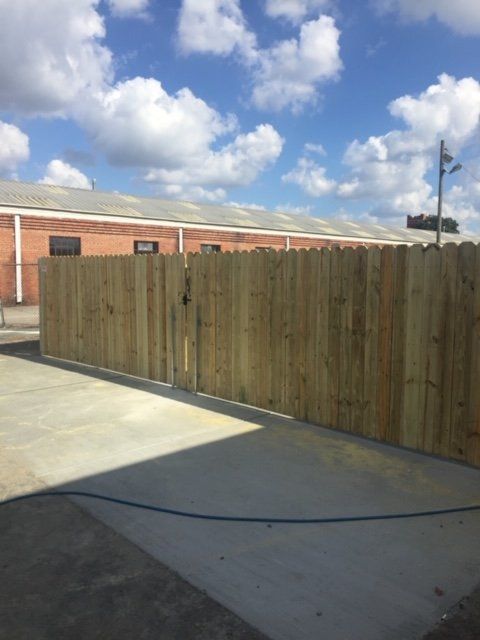 Wooden fence against a brick building on a sunny day.