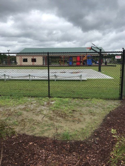 A playground area behind a black fence. The sky is overcast.