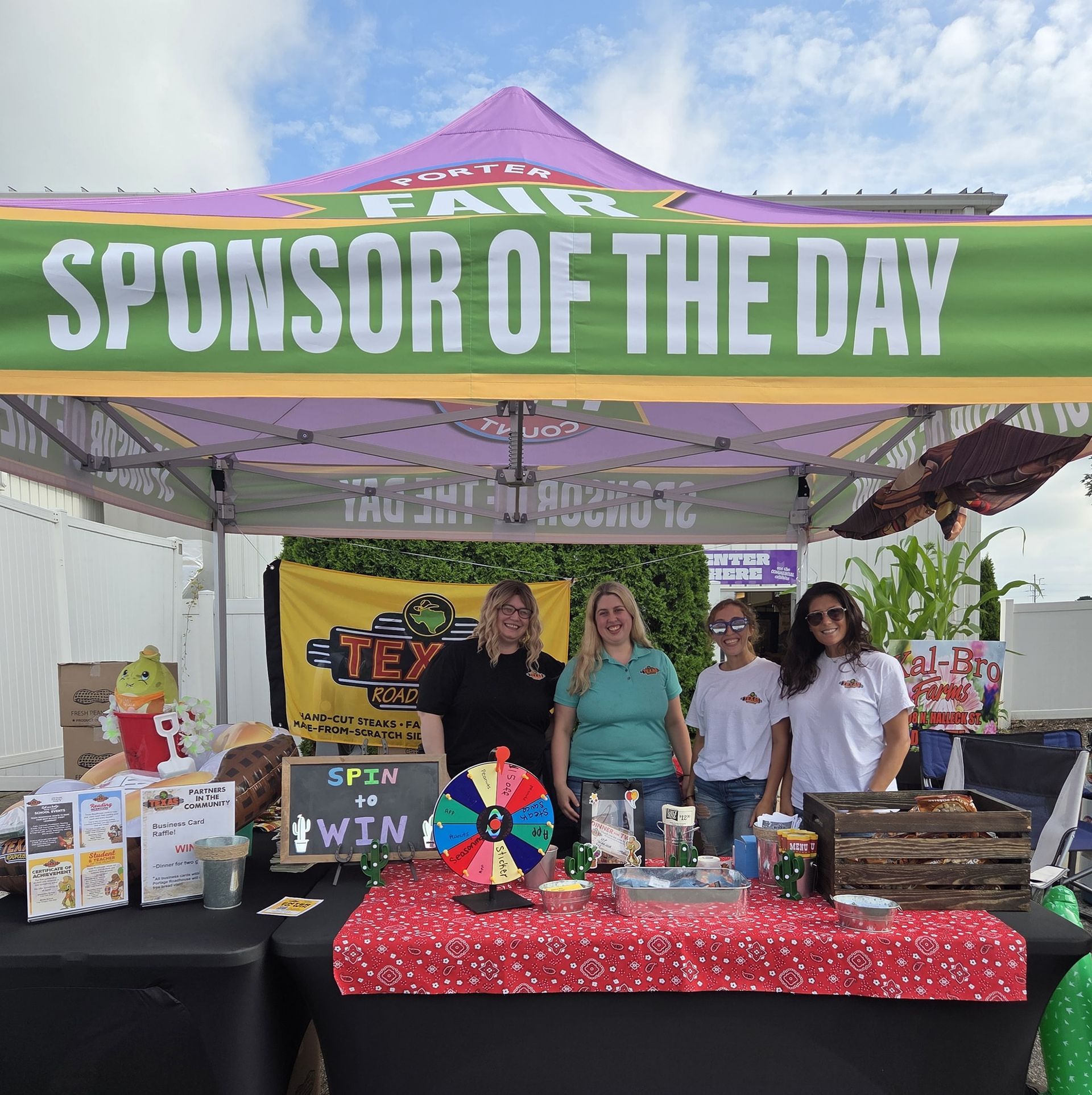 Four people stand at a fair booth under a 