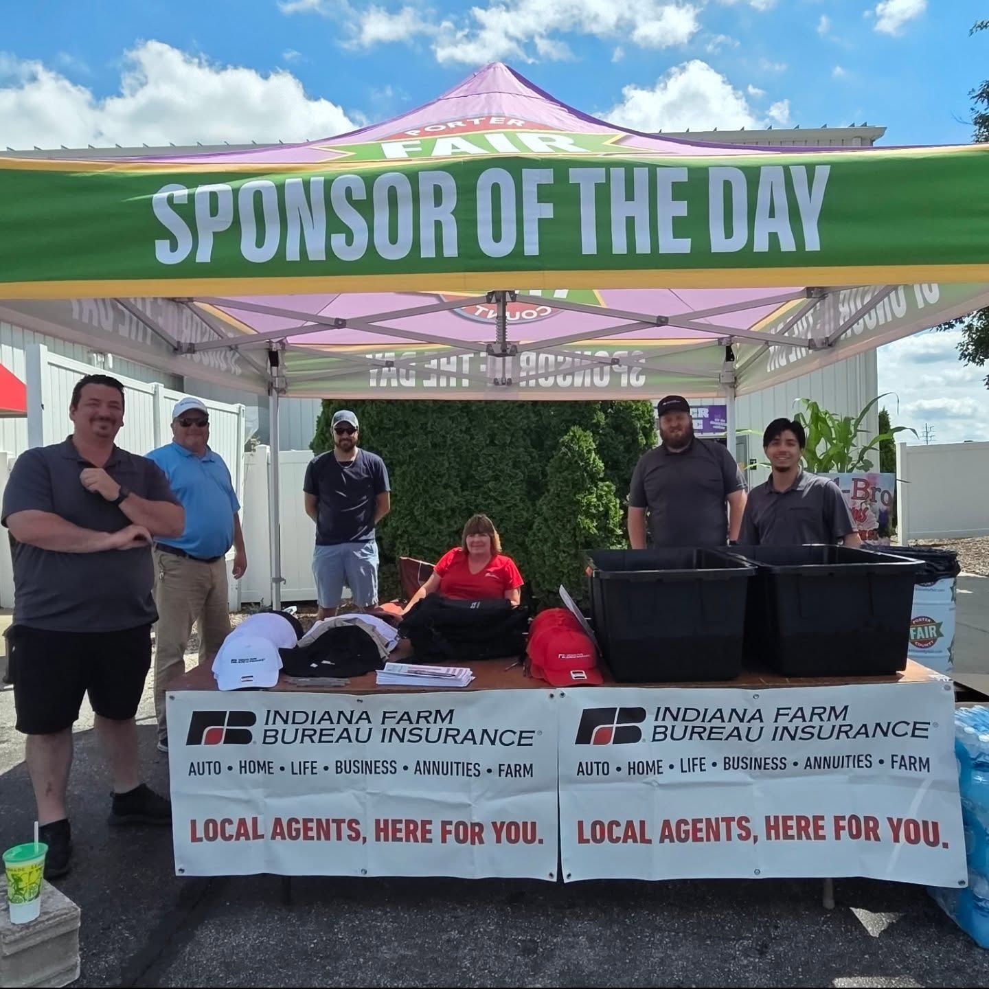 People at an Indiana Farm Bureau Insurance booth at a fair. A banner says 