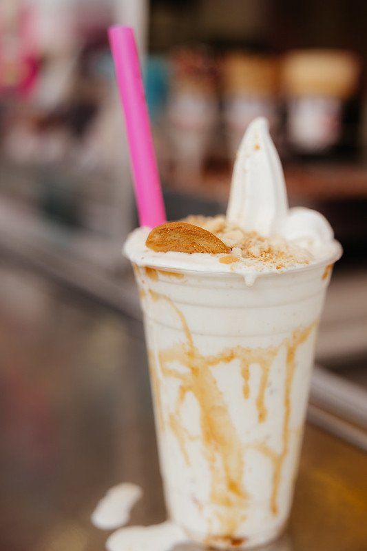 Creamy milkshake with a pink straw, topped with cookie and sprinkles.