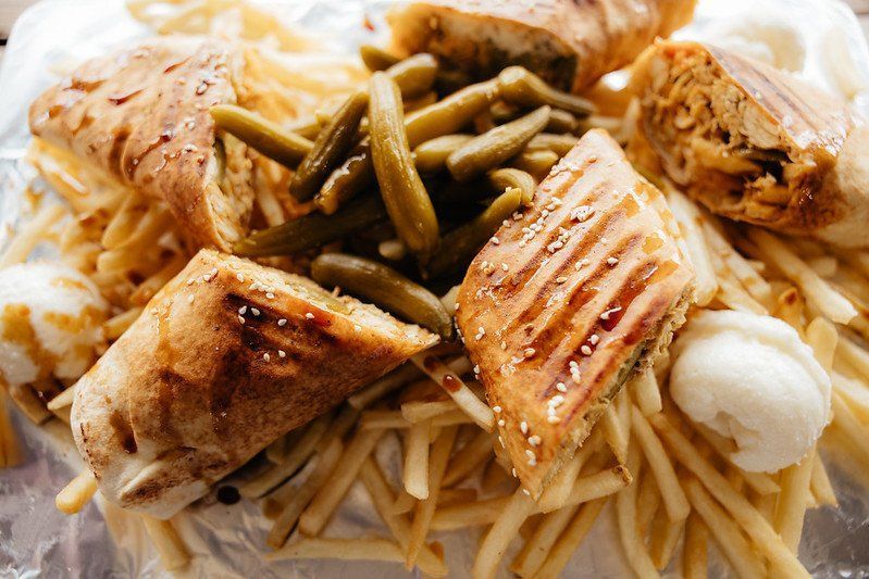 Grilled sandwich with fries, pickles, and sauce.