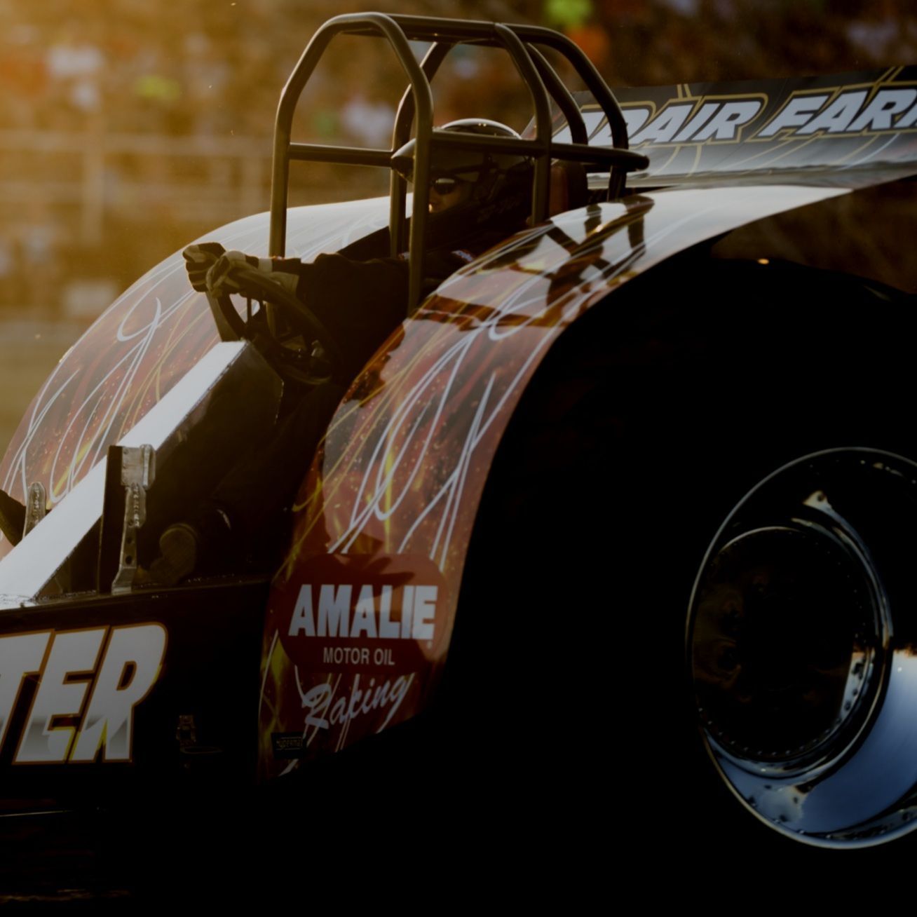 Race car, partial view, black with red flames, 'Amalie Motor Oil' logo, roll cage.