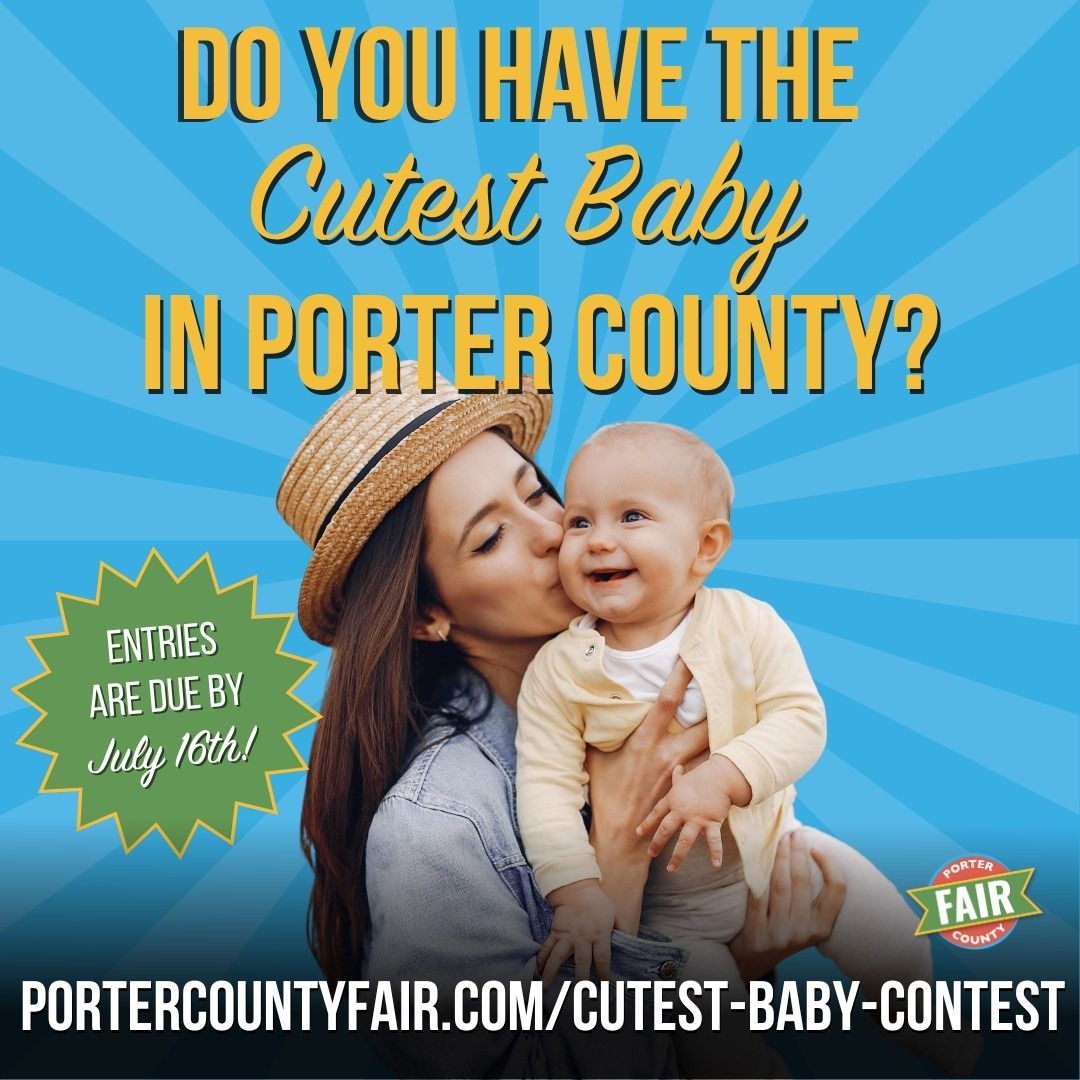 Four people pose in front of a fair sign with flowers. Building in background.