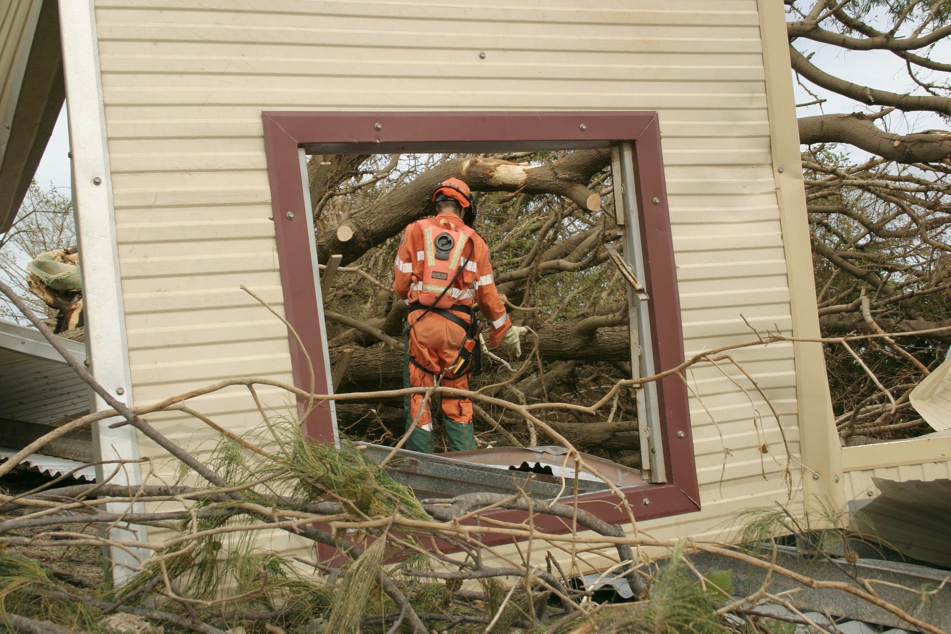 A man in a helmet is standing in a window of a house.