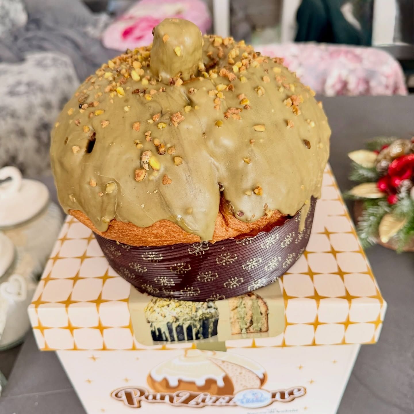 Panettone glassato al pistacchio su una scatola decorata. Colori marrone e verde.