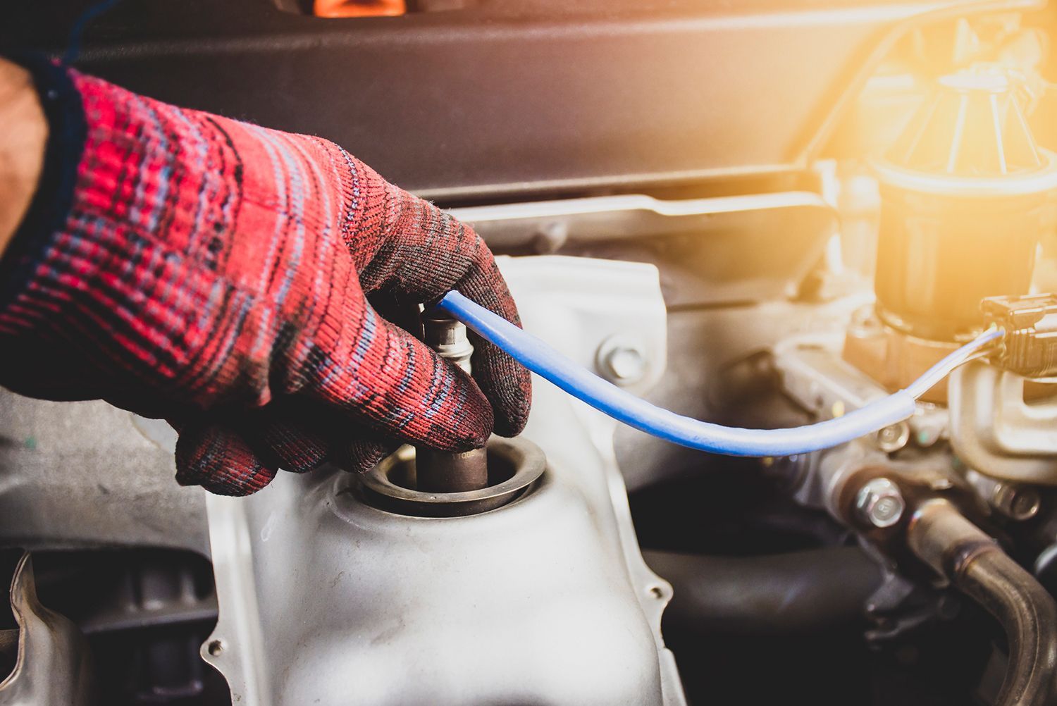 A person wearing gloves is working on a car engine.