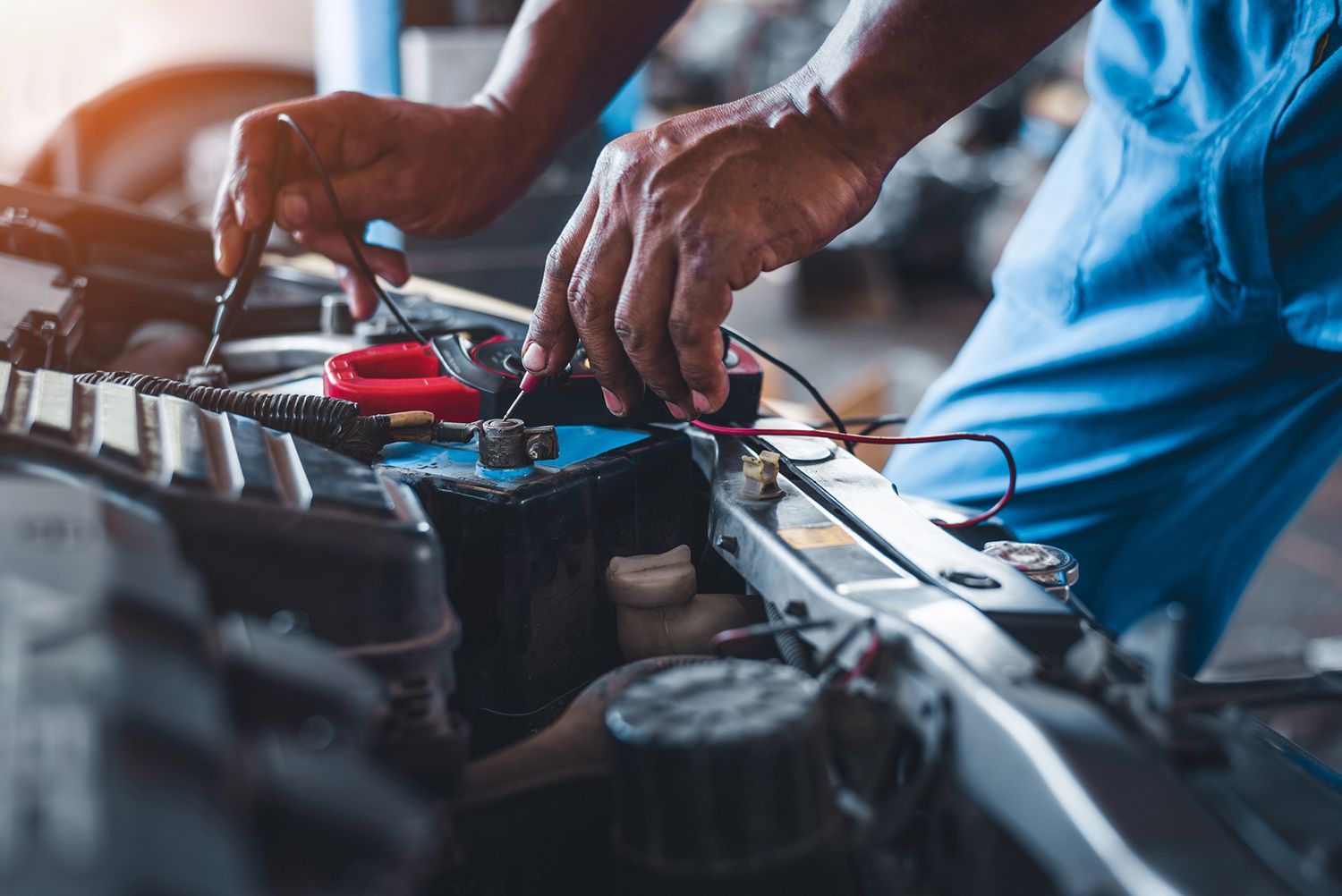 A man is working on a car battery in a garage.