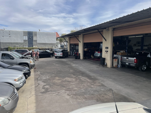 A lot of cars are parked in front of a garage.