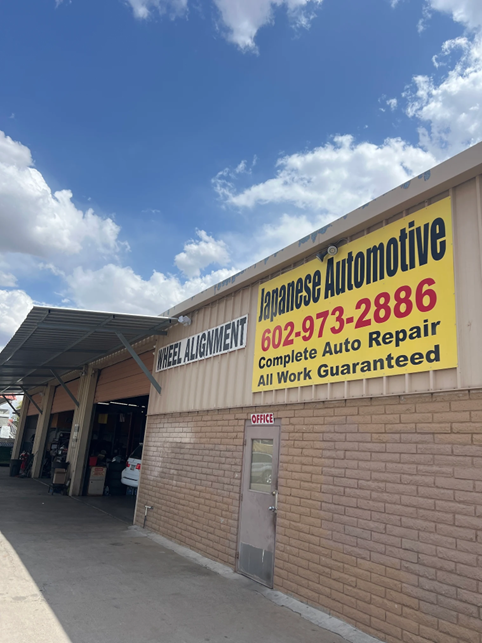 A brick building with a yellow sign that says japanese automotive on it.