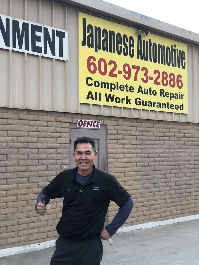A man giving a thumbs up in front of japanese automotive