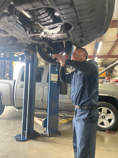 A man is working under a truck on a lift in a garage.