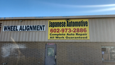 A brick building with a yellow sign that says japanese automotive wheel alignment