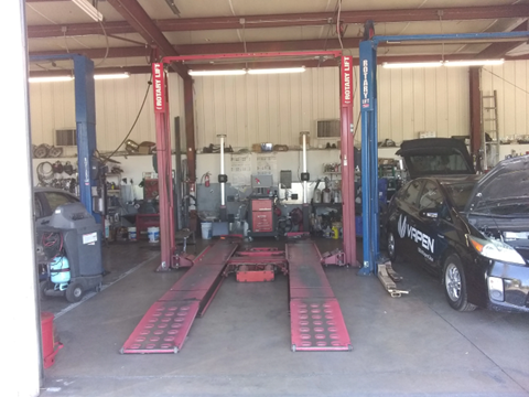 A car is sitting on a lift in a garage.