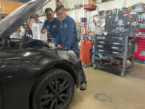Two men are working on a car in a garage.
