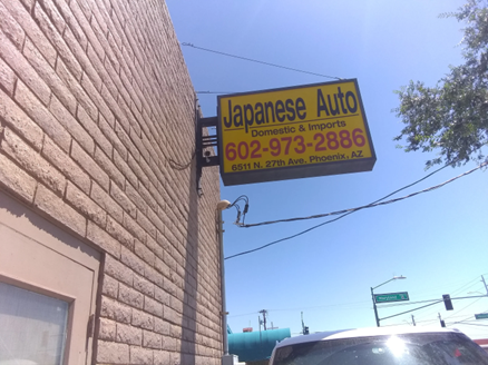 A sign for japanese auto hangs on the side of a building