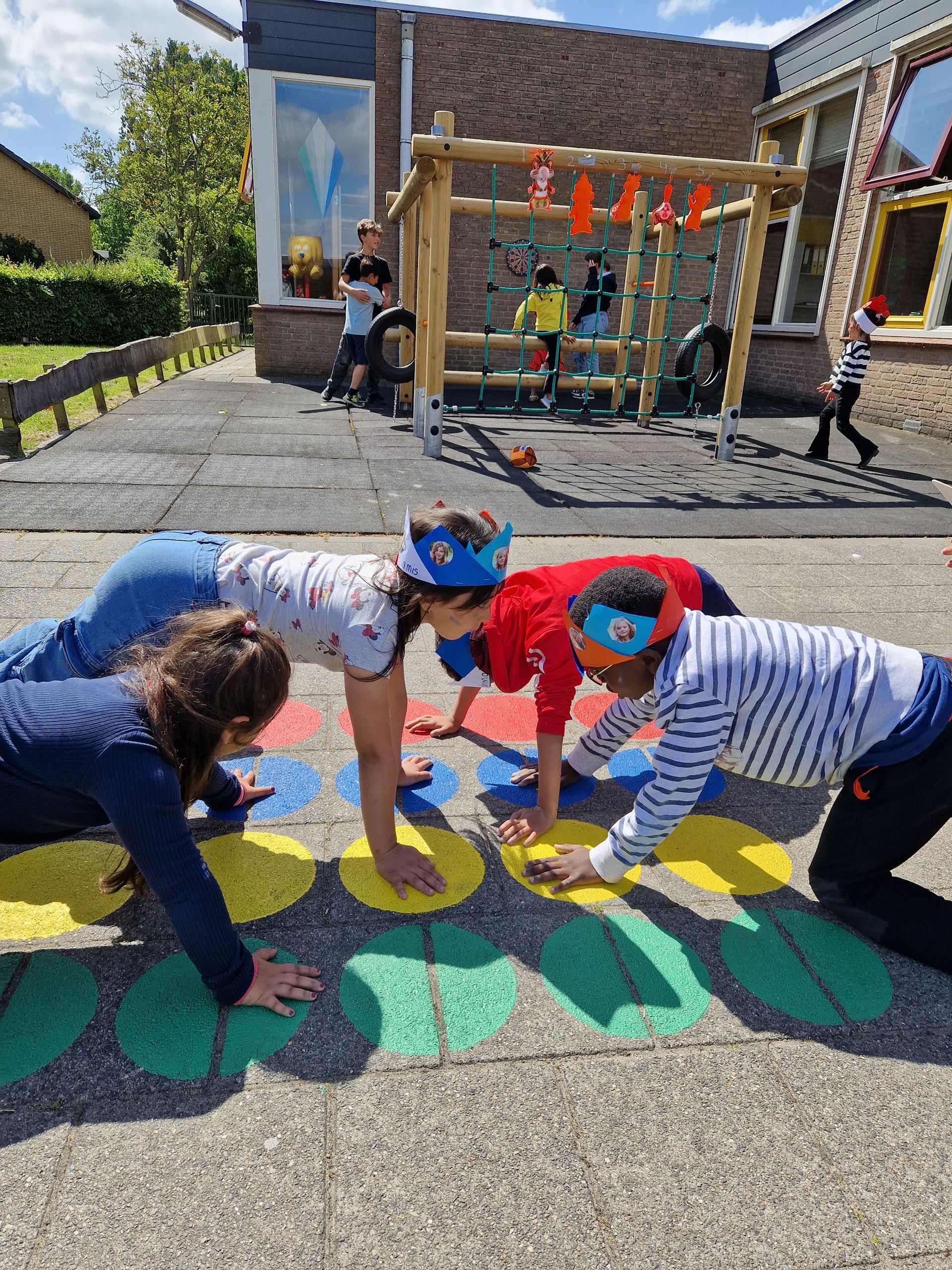 A group of children are playing a game of twister on the ground.