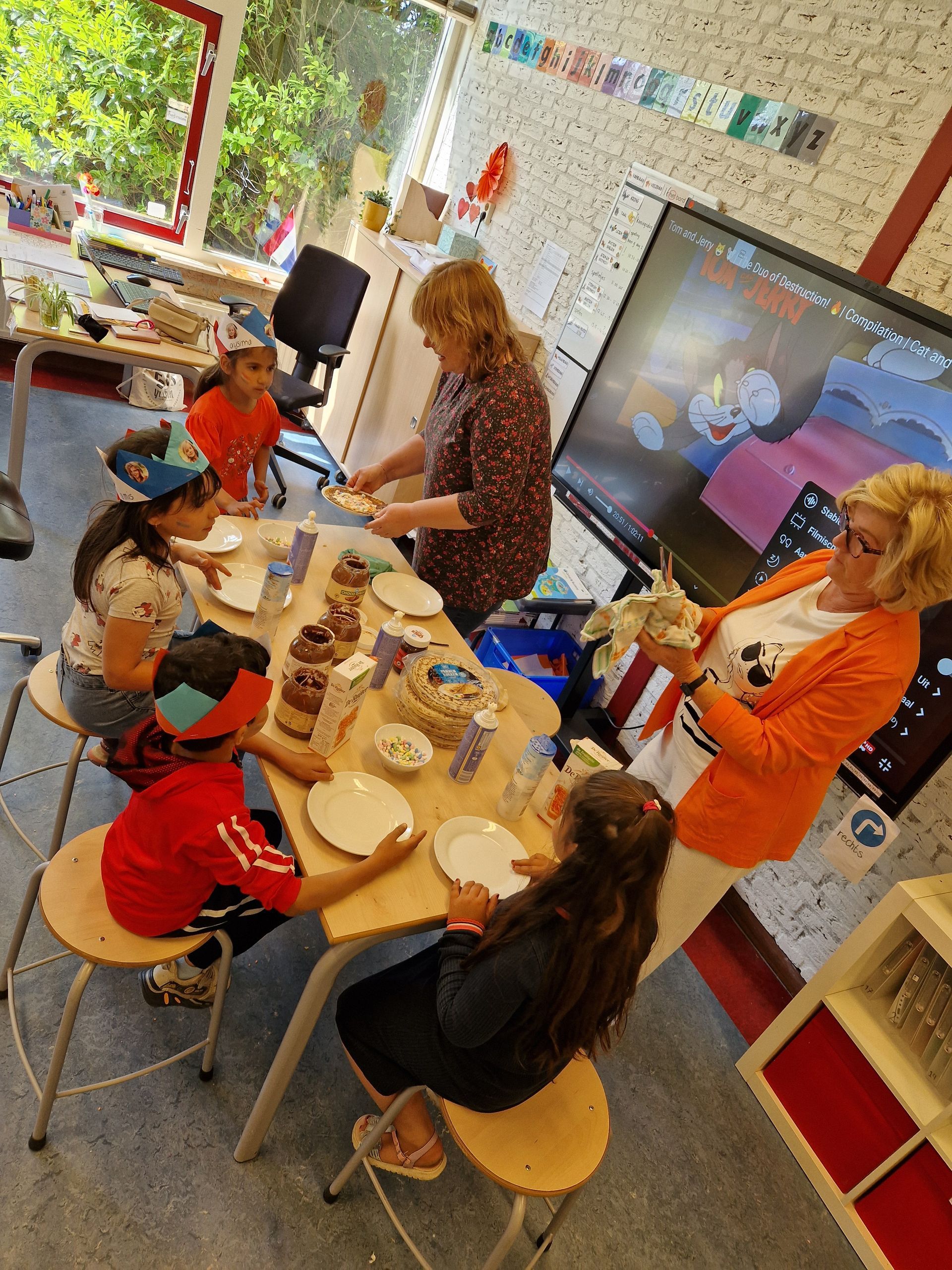 A group of children are sitting around a table with plates of food