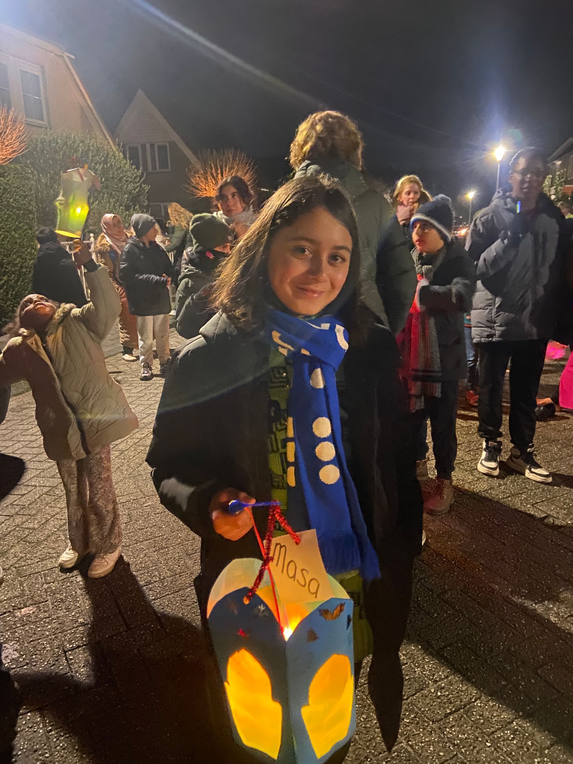 A girl is holding a lantern in front of a crowd of people.